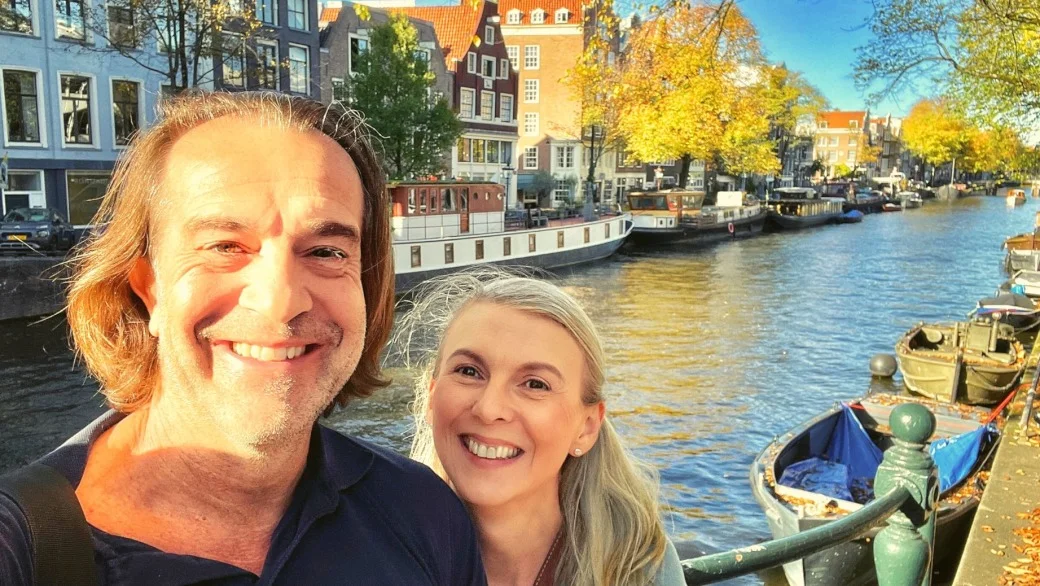 Praxis für Paartherapie - SJS Beratung, Titelbild der SJS Beratung: Oliver und Sabine stehen, Arm in Arm, vor einer Gracht in Amsterdam.