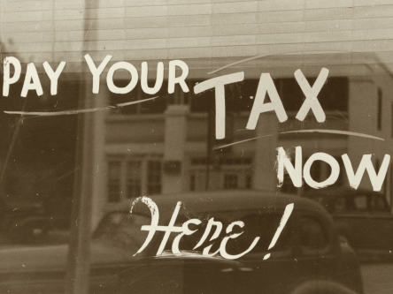 Honorar - Umsatzsteuer (Symbolfoto) : Auf einem Schaufenster steht "Pay your tax here. SJS Beratung, Praxis für Paartherapie